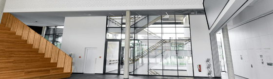 Mehrgeschossiger Gebäudeinnenraum mit offenen Galerien, Treppen, Glasflächen und Akustikdecken