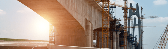 Brückenbau im Infrastrukturbereich mit Betontragwerk, Stützen und Baustellenkränen
